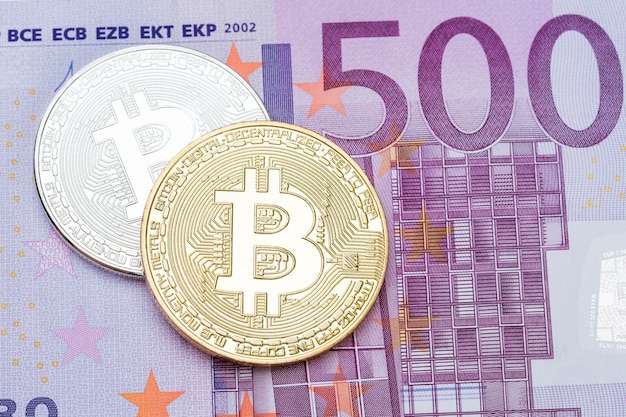 Bitcoin plateado y dorado sobre fondo de billetes de 500 euros