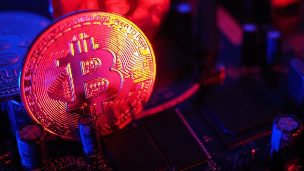 Bitcoin y semiconductores. Representar la minería en criptomonedas causa el calentamiento global. Bitcoins en la placa de la CPU. Bitcoin de primer plano con luz azul y rosa. placa de circuito con moneda. Concepto de activos en línea.