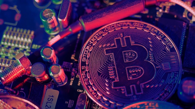 Bitcoin y semiconductores. Representar la minería en criptomonedas causa el calentamiento global. Bitcoins en la placa de la CPU. Bitcoin de primer plano con luz azul y rosa. placa de circuito con moneda. Concepto de activos en línea.