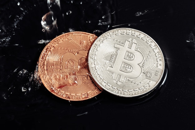 Bitcoin sobre fondo negro. Lavado de Bitcoin con agua. Crisis económica.