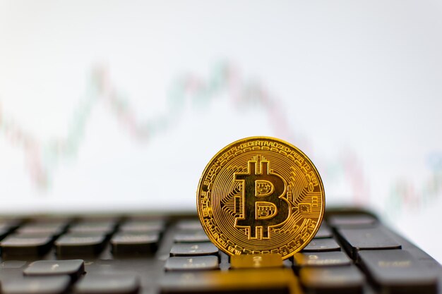 Bitcoin en el teclado y un gráfico de fondo