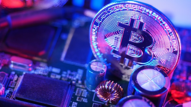 Bitcoin und Halbleiter. Stellen Sie den Bergbau in Cryptocurrency dar, der die globale Erwärmung verursacht. Bitcoins auf CPU-Platine. Nahaufnahme Bitcoin mit blauem und rosa Licht. Platine mit Münze. Online-Asset-Konzept.