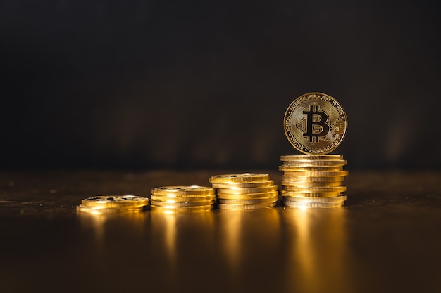 Bitcoin-Wachstum, Bitcoin-Münzen auf schwarzem Goldgrund gestapelt