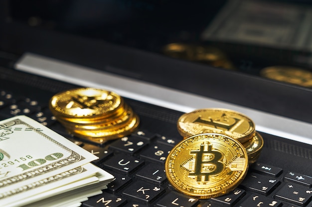 Bitcoins y billetes en el teclado de la computadora de cerca