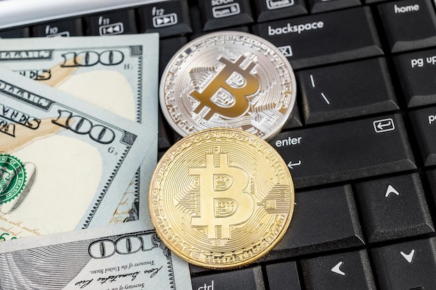 Bitcoins com notas de dólar no teclado do laptop