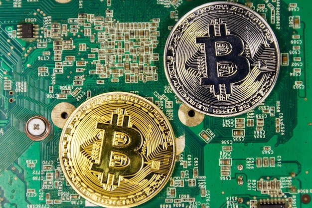 Bitcoins dorados y plateados en una placa base de computadora. Dinero virtual de criptomonedas