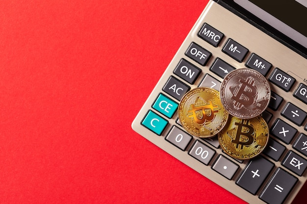 bitcoins e calculadora em uma mesa vermelha