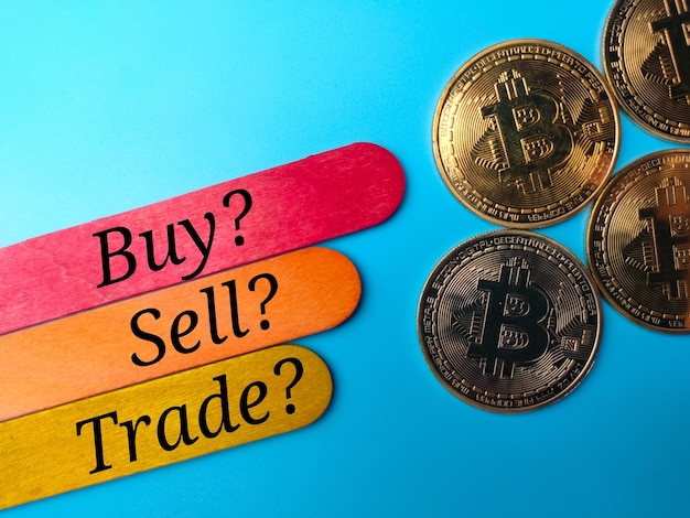 Bitcoins e palitos de sorvete coloridos com texto BUY SELL TRADE em fundo azul