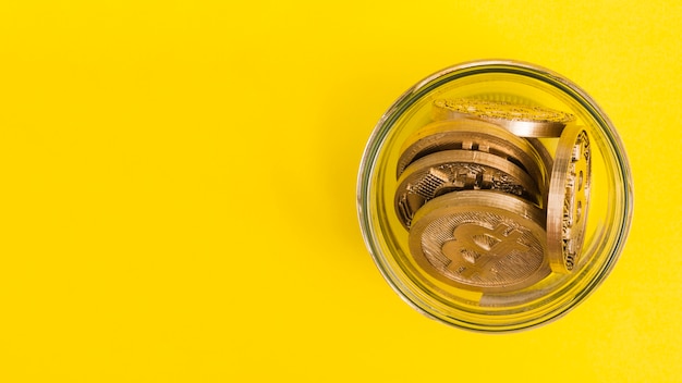 Bitcoins en el frasco de vidrio sobre fondo amarillo