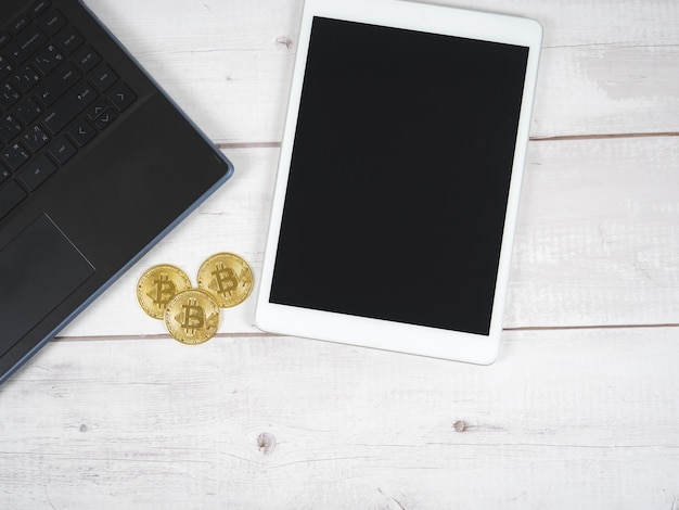 Bitcoins con laptop y tableta en la mesa de madera vie