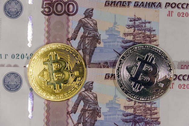 Bitcoins de oro y plata sobre fondo de billetes de quinientos rublos rusos