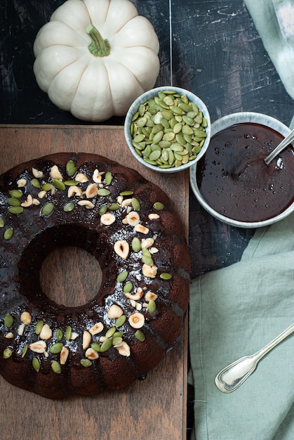 Bizcocho de calabaza y chocolate con un plato de semillas de calabaza al lado.