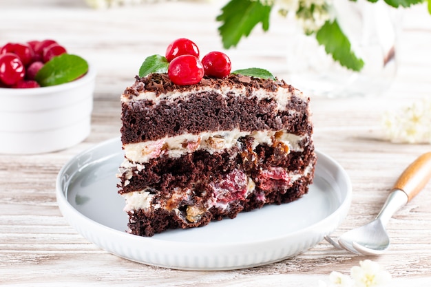 Bizcocho de chocolate en capas con cerezas en un plato sobre una mesa de madera