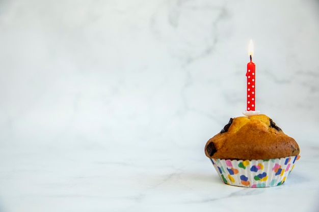 Bizcocho de cumpleaños con una vela de pastel de cumpleaños roja sobre un fondo blanco con espacio de copia a un lado