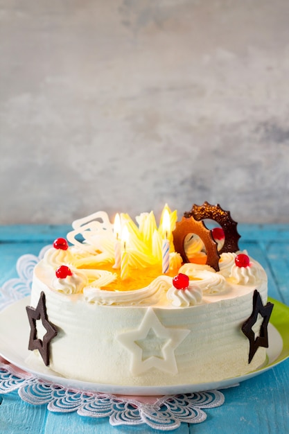 Bizcocho de pastel de cumpleaños con crema batida con velas de colores sobre un fondo azul Copie el espacio