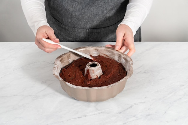 Sacar la masa con una cuchara de masa en un molde para cupcakes forrado con moldes  para muffins de papel de tulipán para hornear muffins de avena y plátano