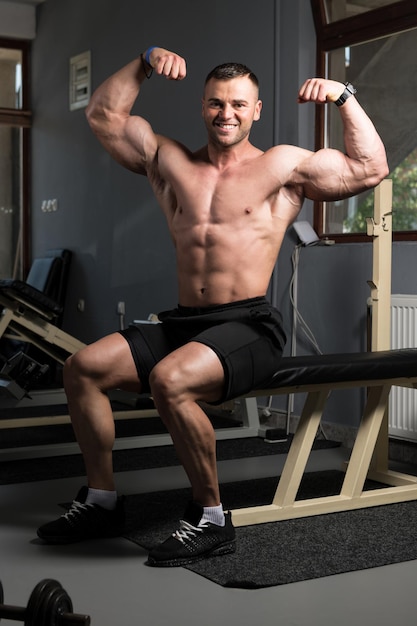 Bizeps-Pose eines jungen Mannes im Fitnessstudio