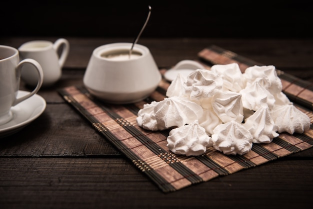 Bizet auf einem braunen Holztisch mit einer Tasse Tee, Zucker und Milch