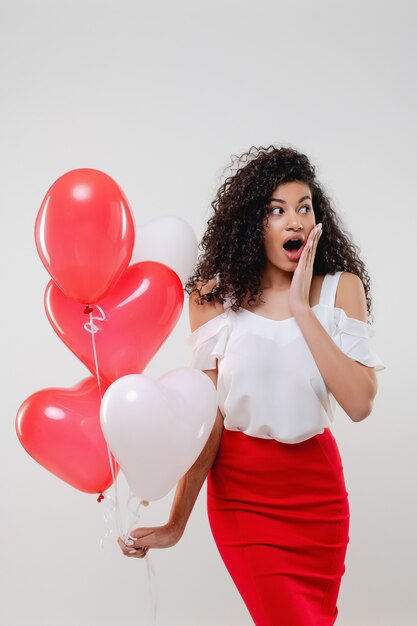 Bkack mujer con coloridos globos en forma de corazón rojo aislado