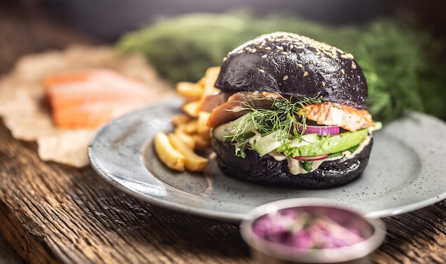 Foto black burger gefüllte lachs avocado und gurkensalat mit pommes.