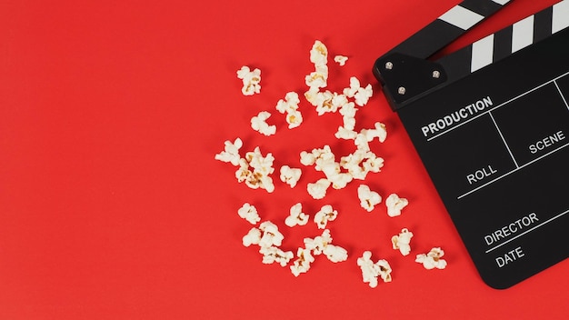Black Clapper Board oder Filmtafel und Popcorn auf rotem Grund.