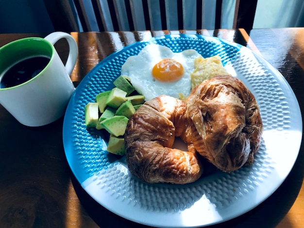 Foto black coffee spiegelei und avocado auf dem tisch. die morgensonne fällt auf den tisch