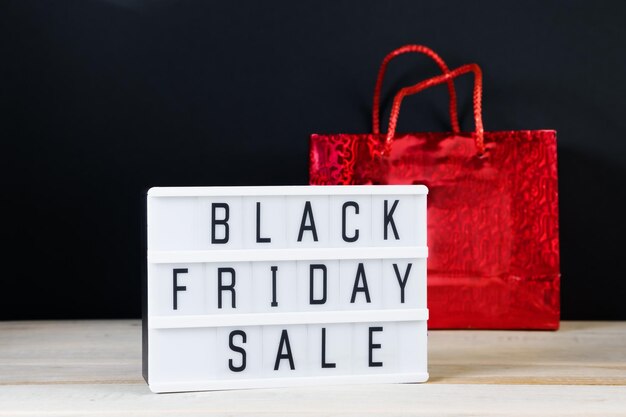 Black Friday Sale Rote Einkaufstasche und Lightbox auf dunklem Hintergrund
