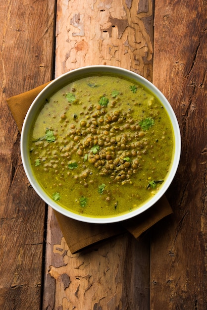 Black Masoor Dal fry o Dhaba Style Sabut Red Lentil dhal tadka en curry verde, servido en un tazón. enfoque selectivo