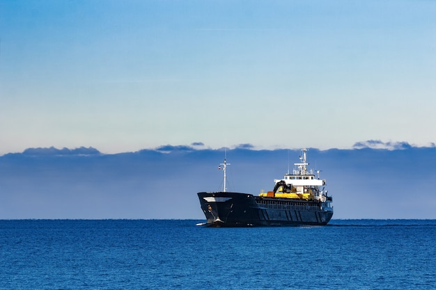 Black Sailing Bulk Carrier. Frachtschiff mit Bagger mit großer Reichweite, der sich im stillen Wasser am sonnigen Tag durch das Meer bewegt