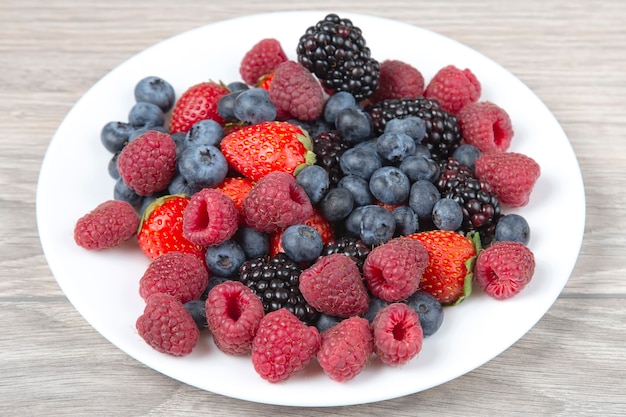 Blackberry, frambuesa, arándano y fresa en una placa blanca.