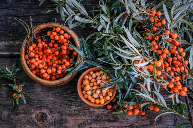 Blätter und Beeren des orange Sanddorns auf Holztisch