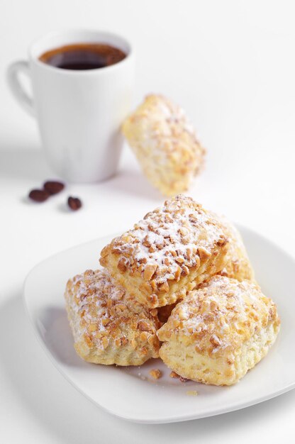 Blätterteigplätzchen mit Nüssen und Tasse Kaffee auf weißem Hintergrund