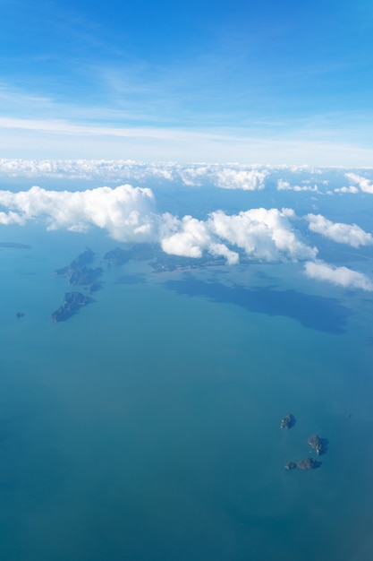 Blancas nubes esponjosas vuelan sobre el océano y las islas. Foto del avión.