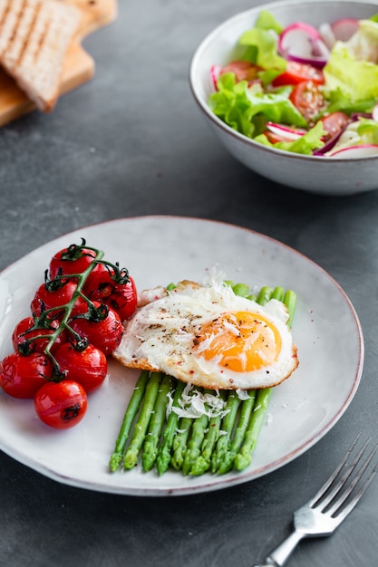 Blanchierter Spargel, Spiegelei, Tomaten und Sald auf der Schüssel.