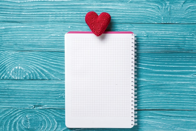Blank Notepad für Kopie Raum und Vintage handmaded Valentinstag Spielzeug weißes Herz über blauem Holz Hintergrund