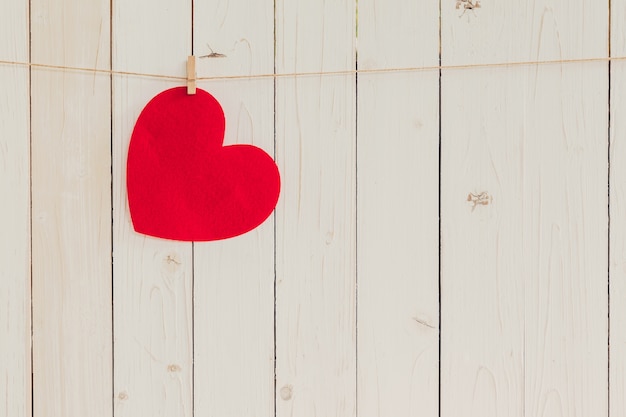 Blankes rotes Herz hängt auf weißem Holz mit Platz für Valentine und Hochzeit Hintergrund.