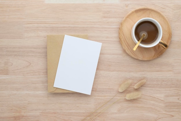 Blanko-Papierkarten, Blanko-Grußkarten-Einladung Mockup mit getrocknetem Hasenschwanzgras und Kaffeetasse auf Holztisch, Holzschreibtischhintergrund, Minimale Holztisch-Arbeitsplatz-Komposition, flache Lage, Attrappe