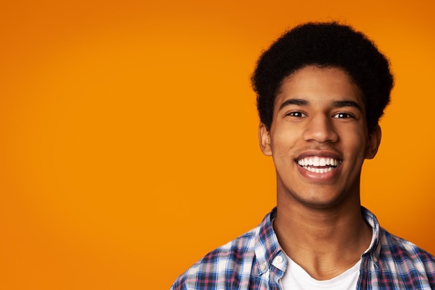 Blanqueamiento de dientes afro chico sonriendo ampliamente en estudio