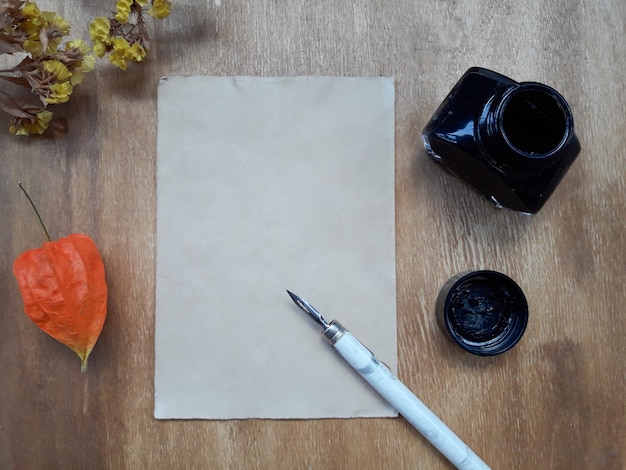 Blatt Papier, ein Tintenfass und trockene Blumen