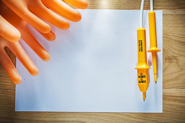 Blatt Papier elektrische Tester isolierende Schutzhandschuhe auf Holzplatte.