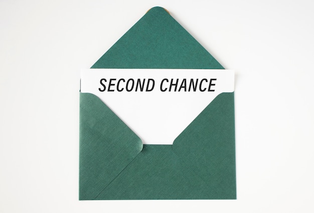 Blatt Papier mit Text: Zweite Chance, in einen grünen Umschlag eingelegt.