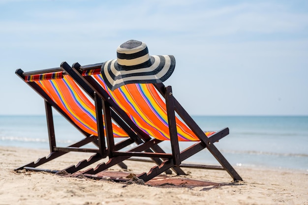 Foto blau-weiß gestreifter strandhut, strandkorb, zwei strandkörbe am tropischen sandstrand, sommerreiseurlaub und sommerurlaubskonzepte