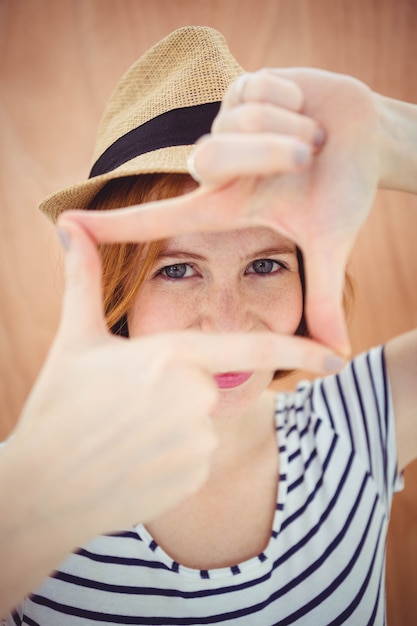 blauäugiger Hipster in einem Trilby, durch ihre Hände schauend