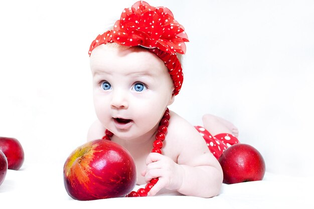 Blauäugiges Baby mit roten Perlen und Äpfeln