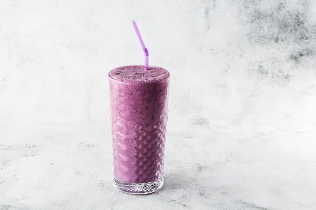 Blaubeer-Smoothie oder Purpurmilchshake der schwarzen Johannisbeere im Glas auf hellem Marmorhintergrund. Draufsicht, Speicherplatz kopieren. Werbung für Milchshake-Café-Menü. Coffeeshop-Menü. Horizontales Foto.