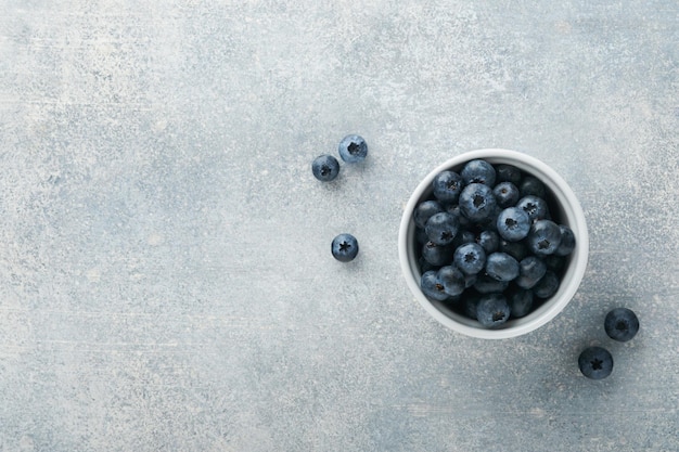 Blaubeere Weiße Schale mit frischen Blaubeeren auf grauem Steinhintergrund Tisch Leckere reife Blaubeeren Platz für Text Lebensmittelhintergrund Ansicht von oben