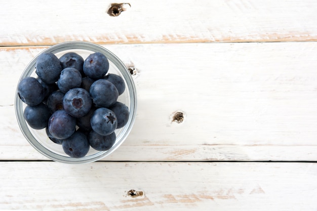 Blaubeeren in der Kristallschale auf Draufsicht des weißen Holzes