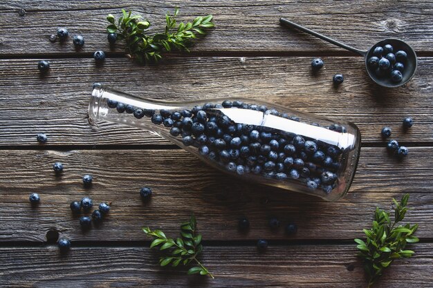 Blaubeeren in einer Flasche auf Holz