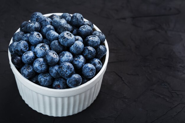 Blaubeeren in einer weißen Tasse auf einem schwarzen