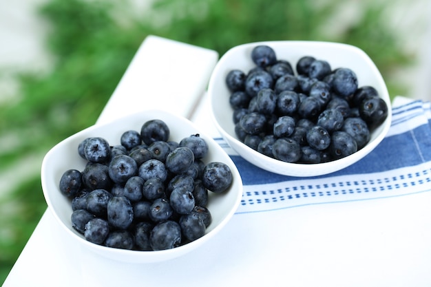 Blaubeeren in Tellern auf Serviette auf Holztisch auf Gras